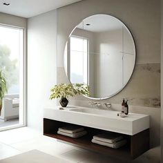 a bathroom with a large round mirror above the sink and a potted plant next to it