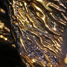 gold and black sequins on fabric with lights in the backgroung