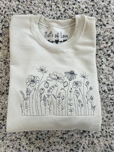 Tot's of love  These beautiful wildflower sweatshirt  Great for birthday Gifts for someone special  Jumper colours  Stone  Black White  Baby pink  Grey  Dusty green  Can be personalised with details under the wildflower design  We can do any colour of thread so if there is a colour you would like please leave when leaving the details for the personalisation Size run  S-34/36in M - 38/40in  L-42/44in Xl-46/48in Xxl-50-52in We have a list of fonts which if you leave the font you would like when. L Spring Crew Neck Sweatshirt, Spring Crew Neck Sweatshirt For Gift, Crew Neck Sweatshirt For Spring, Spring Cotton Sweatshirt Gift, Custom Embroidery Spring Tops As Gift, Spring Custom Embroidered Top As Gift, Custom Embroidered Tops As Spring Gift, Custom Embroidered Top For Gift In Spring, Spring Gift Long Sleeve Sweatshirt