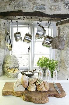 a kitchen counter with pots and pans hanging from the ceiling above it, along with bread on a cutting board