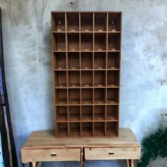 a wooden shelf with two drawers and one drawer on the bottom, next to a plant