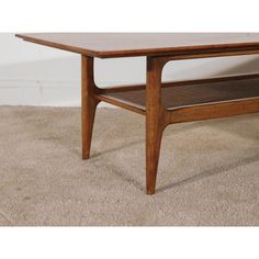 a wooden coffee table sitting on top of a carpeted floor next to a wall