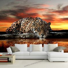 a living room scene with a couch and a large leopard on the water at sunset