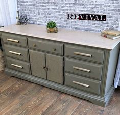 an old dresser is painted green with gold handles and knobs on the top, next to a brick wall