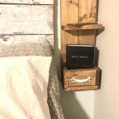 a small wooden shelf on the wall above a bed with a book and an mp3 player