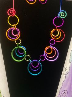 A rainbow of color in circles make up this fun and funky necklace.  Length is about 20 inches and the closure is looping the ring on the side over the aluminum swirl.  photo is an example.  Yours will be in random  multi colors.   earrings are sold separate.  Check listings Cheap Multicolor Festival Jewelry, Cheap Rainbow Color Fun Necklaces, Cheap Multicolor Plastic Necklaces, Handmade Fun Metal Jewelry, Fun Handmade Metal Jewelry, Rainbow Wire Wrapped Round Jewelry, Multicolor Metal Necklaces With Unique Variations, Rainbow Metal Jewelry For Jewelry Making, Multicolor Wire Wrapped Metal Necklaces