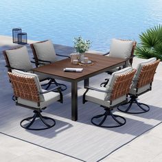 an outdoor dining table with chairs around it near the water and palm tree in the background