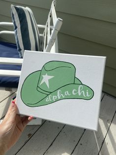 a person holding up a green hat on top of a wooden decking area next to a chair