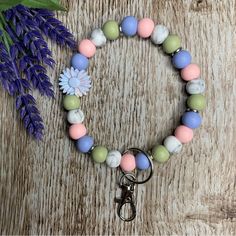 a close up of a bracelet on a table with flowers and a keychain