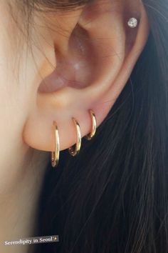 a close up of a person wearing gold ear cuffs with diamond studs on them