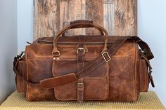 "Genuine Leather Travel Duffel Bag. PURE LEATHER: Bags are made of full grain genuine leather. Vintage inspired design combined with the distressed leather gives a rich classy look. Inside of the bag is lined. One zippered pocket inside of the bag, three pockets outside of the bag. SIZE: 22''x 11.5'' x 11\" Open Pockets within the front pocket can be a great place for your belongings like mobile phone, wallet, headphones. Use it for a mini vacation, gym or for just running around town; this leat Travel Satchel In Textured Vegetable Tanned Leather, Leather Bags For Overnight Trips, Leather Satchel Backpack For Trips, Leather Duffle Bag With Leather Lining For Trips, Leather Satchel For Trip, Leather Duffle Bag With Leather Lining, Leather Duffle Bag With Shoulder Shape, Leather Duffle Bag With Shoulder Strap, Leather Duffle Bag With Shoulder Strap And Leather Lining