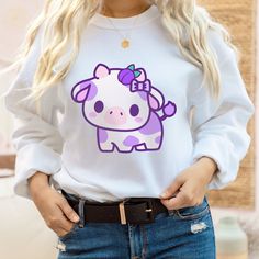 PLEASE NOTE: This is a adult UNISEX sweater. If you want an oversized look then consider ordering up a size. This cute plumberry cow sweater will look adorable on you! Makes for a great kawaii gift for your loved ones as well. The collar is ribbed knit, so it retains its shape even after washing. There are no itchy side seams on these sweaters. .: 50% cotton, 50% polyester .: Medium-heavy fabric (8.0 oz/yd² (271.25 g/m .: Loose fit .: Sewn-in label .: Runs true to size Oversized White Kawaii Sweatshirt, Oversized Kawaii Long Sleeve Sweater, Cute Long Sleeve Sweatshirt With Character Print, Casual Purple Sweatshirt With Cartoon Print, Oversized Kawaii Sweatshirt With Cartoon Print, Oversized Kawaii Cartoon Print Sweatshirt, White Harajuku Sweatshirt With Cartoon Print, Kawaii Cotton Sweatshirt For School, Cotton Kawaii Sweatshirt For School