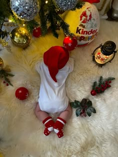 a baby is laying on the floor next to christmas decorations