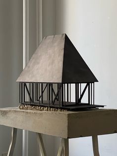 a model of a house sitting on top of a wooden table next to a white wall