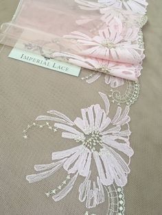 the table cloth has been embroidered with flowers on it and is next to an empty tag