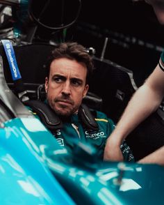 a man sitting in the drivers seat of a racing car with his hand on the steering wheel