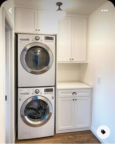 a washer and dryer are in the corner of this laundry room with white cabinets