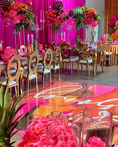 an elaborately decorated banquet hall with pink and orange flowers in vases on the tables