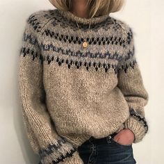 a blonde woman wearing a sweater and jeans