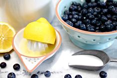 a bowl of blueberries and a lemon on a table