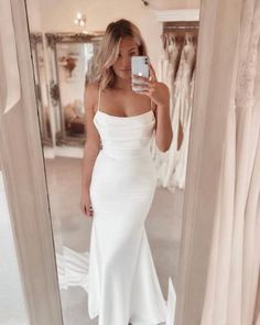 a woman taking a selfie in front of a mirror wearing a white dress and high heels