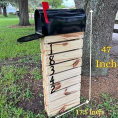 a wooden box with numbers on it sitting in the grass next to a large tree