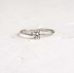 a diamond ring sitting on top of a white surface