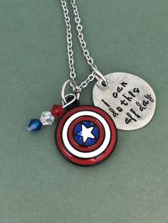 Show the Captain America pride with this hand-stamped necklace. The stamped charms are made of pewter and are approximately 3/4 inch in diameter. The chains are 20 inches long and are made of stainless steel.  The necklaces come ready to give, packaged in a hand-stamped brown cardboard box. View more items in my shop:  http://www.etsy.com/shop/dustlily Captain America Jewelry, America Pride, The Mighty Thor, Hand Stamped Necklace, California Love, Thors Hammer, Colored Gems, Photo Bracelet, Captain Marvel