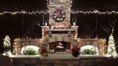 an outdoor fireplace is lit up with christmas lights and wreaths on the mantel