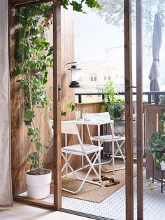 two white chairs sitting on top of a wooden floor next to a table and potted plants