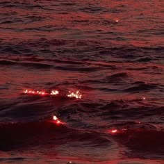 some red lights floating in the water at night with a square frame over it that says,