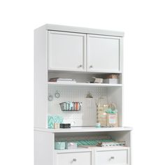 a white cabinet with drawers and other items on the top shelf in front of it