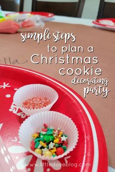 two paper cups filled with candy sitting on top of a red tray next to a christmas tree