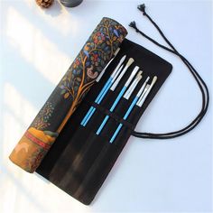 an assortment of pens and pencils are on a black case next to some pine cones