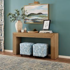 a living room with blue walls and a painting on the wall above two stools