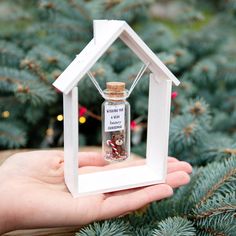 someone is holding a miniature house in their hand and it has a message on the bottle