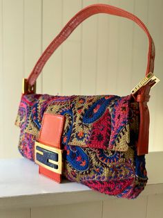 Orange and multicolor embroidered Fendi Paisley Baguette with gold tone hardware, leather trim and flat shoulder strap. Satin lining with flat pocket at interior and magnetic closure at front. Very good condition: Dior Shoes, Chanel Handbags, Leather Trim, Magnetic Closure, Leather Trims, Paisley, Gold Tones, Shoulder Strap, Fendi