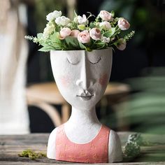 a vase with flowers in it sitting on a table next to a potted plant