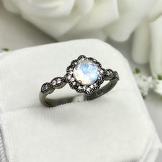 This beautiful ring is made from genuine 925 sterling silver with Black Rhodium plating. Ring details- -The Main stone is a round cut 6.5mm Natural Rainbow Moonstone Stone -Side stones are round 1.1mm simulated diamonds -Ring is casted in solid 925 sterling silver with Black Rhodium plating ( Rose Gold, yellow gold and White rhodium plated also available, please check the drop down menu for more options) -The Total face height of the ring measures 9mms and the band width measures 2mms -Each ring Silver Diamond Moonstone Ring For Promise, Silver Moonstone Ring With Diamond In Fine Jewelry Style, Silver Opal Ring With Accent Stones, Round Cut, Fine Jewelry Sterling Silver Moonstone Ring, Round Jewelry With Stone Setting For Promise, Anniversary Fine Jewelry Moonstone Ring, Silver Sterling Moonstone Wedding Ring, Silver Opal Promise Ring With Accent Stones, Fine Jewelry Round Moonstone Promise Ring