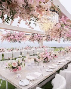 an outdoor dining area with flowers and chandelier hanging from the ceiling, along with white chairs