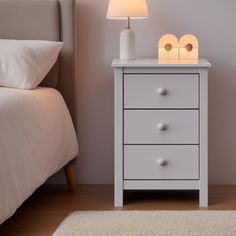 a white night stand next to a bed in a room with a rug on the floor