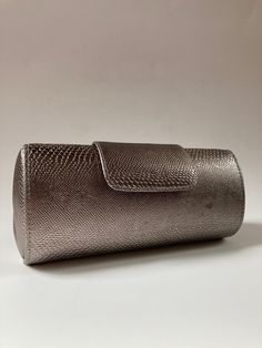 "This is a fun and stylish silver faux-lizard evening bag! The solid body is a cross between a cylindrical barrel bag and a rectangular baguette with flap closure. It has an oval end profile with elasticized gussets. Magnetic snap closure. The interior features an elegant silvery-gray polyester satin lining and one expandable open interior pocket. The cross-body length gray braided cord strap can be tucked inside. Excluding the strap, the case is 4 1/2\" high x 7 3/4\" wide x 2 1/2\" deep. With Metallic Rectangular Clutch For Formal Events, Metallic Rectangular Clutch For Formal Occasions, Silver Clutch With Magnetic Closure, Silver Clutch With Magnetic Closure For Formal Occasions, Formal Silver Clutch With Magnetic Closure, Silver Party Clutch With Magnetic Closure, Lizard Print, Beaded Evening Bags, Oversized Bag