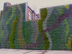 a building covered in green plants next to a sidewalk