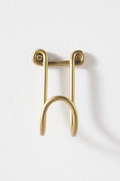 a pair of gold ear clips on a white background with the letter h in the middle