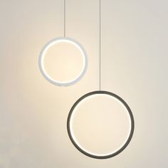 two circular lights hanging from the ceiling in a room with white walls and flooring