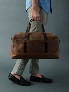 a man carrying a brown leather duffel bag