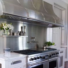 a stainless steel stove top oven sitting inside of a kitchen next to a wall mounted range