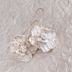 Description Looking for a unique piece? These white flower speckled gold earrings are handmade, lightweight, and jaw-dropping. Gold leaf is hand pressed into each petal for just the right amount of sparkle. These make for a fantastic bridesmaid proposal gift. Details Extremely lightweight Hand pressed gold leaf Hand sculpted from polymer clay Nickel-free Durable Shipping 2-3 weeks During busy seasons, orders of 6 or more pieces may incur a longer turnaround of 4+ weeks; please remember to order White 14k Gold Filled Bridal Earrings For Wedding, 14k Gold Filled White Bridal Earrings For Wedding, White 14k Gold Filled Earrings For Weddings, White 14k Gold Filled Bridal Earrings As Gift, 14k Gold Filled White Bridal Earrings As Gift, Delicate Gold Flower Earrings With Handmade Flowers, Delicate Gold Flower Earrings With Handmade Details, Delicate Handmade Earrings For Bridesmaids, Delicate White 14k Gold Filled Earrings