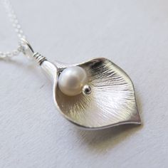 Silver Calla Lily Necklace - Gift for Her Classic and elegant gift for mother, friend or for bridesmaids. Dainty, easy to wear everyday or on special occasions. FEATURES: * A small freshwater pearl is wire wrapped with bright calla lily petal to form a flower pendant. * The petal is rhodium plated over brass. * Comes with sterling silver chain, finished with spring clasp closure. All sterling silver calla lily necklace: https://www.etsy.com/listing/476943360/ MEASUREMENTS: * the pendant is about Elegant White Necklace - Gift For Mom, Elegant Handmade Necklace Gift For Mom, Elegant Handmade Necklace For Mom, Elegant Nickel-free Necklace For Wedding, Elegant Flower Shaped Necklace For Mom, Elegant White Jewelry For Mom's Gift, Elegant White Jewelry As Gift For Mom, Elegant White Jewelry As A Gift For Mom, Elegant Nickel-free Necklaces For Bridesmaid Gift