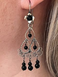 We are excited to feature a collection of Mexican Silver Filigree Earrings from Oaxaca in our store. Each piece is crafted from molten silver, processed and formed into intricate designs, often adorned with exquisite stones. Our artisans, with their skilled hands, create unique pieces that encapsulate a stunning and romantic aesthetic. Adorning these pieces, you're not just wearing jewelry; you're embodying a special, timeless elegance. Materials:  Sterling Silver Gemstone: Black Onyx Drop Length: 2 1/4" long, 1" wide Closure: Ear Wire Elegant Sterling Silver Chandelier Earrings For Festival, Adjustable Filigree Earrings, Black Bohemian Sterling Silver Earrings, Elegant Festival Earrings With Dangling Beads, Artisan Chandelier Earrings For Festival, Artisan Style Chandelier Earrings For Festival, Black Bohemian Pierced Jewelry, Artisan Festival Chandelier Earrings, Elegant Dangle Chandelier Earrings For Festivals